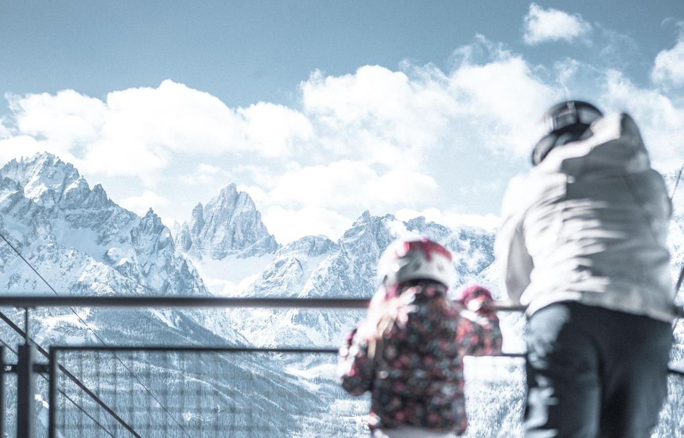 Ein Mann und ein Kind in Skikleidung blicken auf die Dolomiten