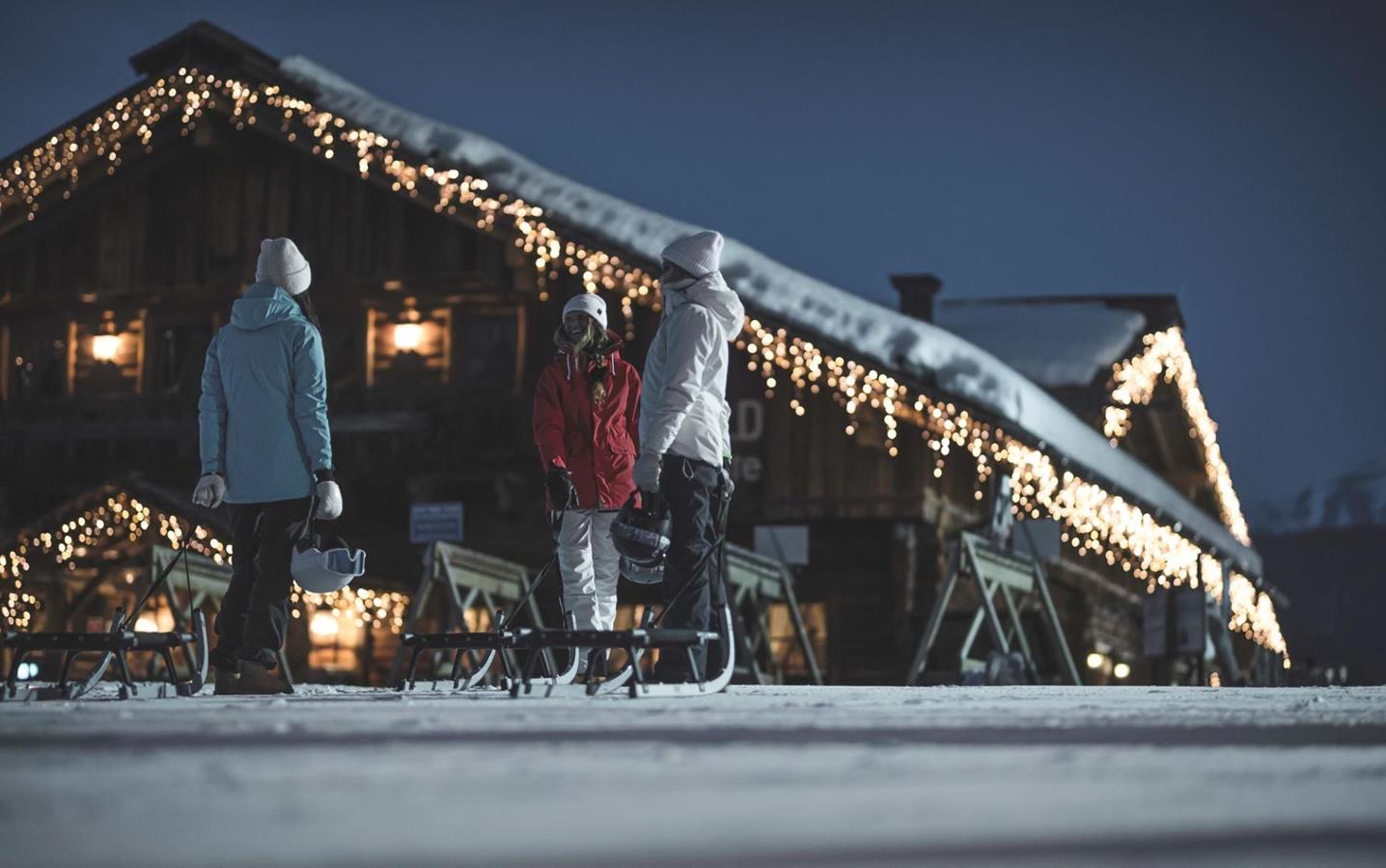 Three people sledding at night