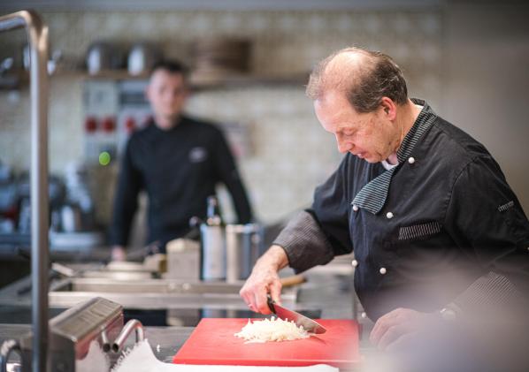 A cook is cutting onions in the kitchen