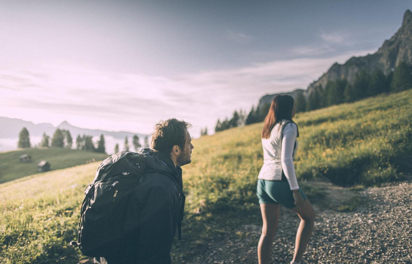 Ein Mann und eine Frau wandern, umgeben von einer weitläufigen Almlandschaft