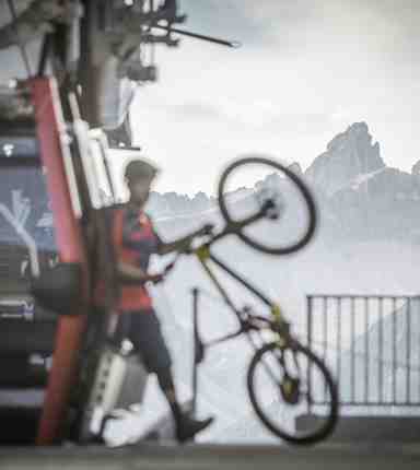 A man is getting out of a cable car with his bicycle