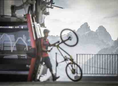 A man is getting out of a cable car with his bicycle