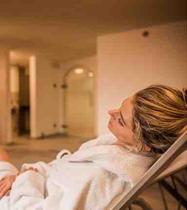 A woman is lying on a deck chair in the relaxation room