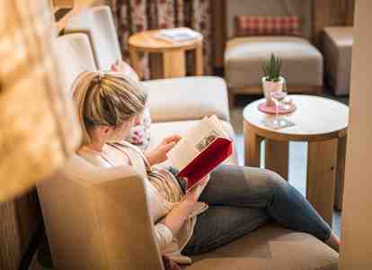 Eine Frau sitzt auf einem Sofa und liest ein Buch