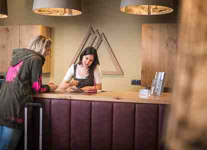 A staff member at the hotel reception is speaking kindly with an arriving guest
