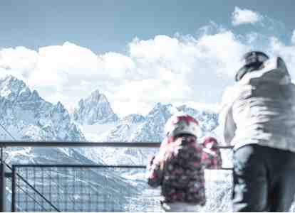 Ein Mann und ein Kind in Skikleidung blicken auf die Dolomiten