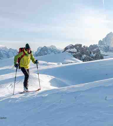 Una persona risale un pendio di montagna innevato con gli sci d’alpinismo attraverso la neve profonda