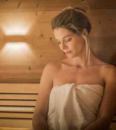 A woman is sitting in a Finnish sauna
