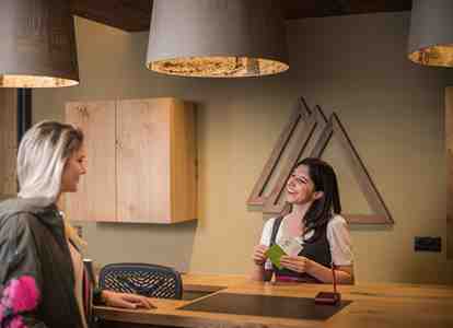 Una dipendente alla reception dell’hotel parla gentilmente con un’ospite in arrivo