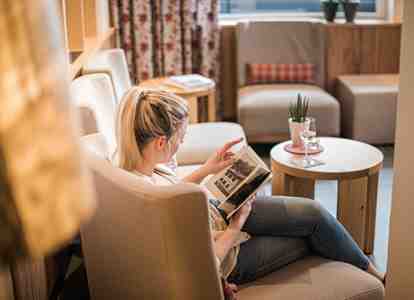 A woman is sitting on a sofa and reading a book