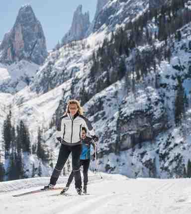 A man and a woman are cross-country skiing in the Dolomites